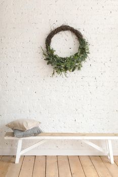 Wreath hanging on white brick wall over bench at home.