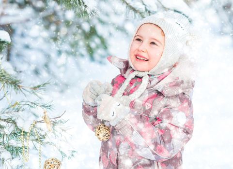 Little smiling girl decorating christmas tree outdoor