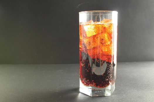 Coca-Cola kvass in an iced glass on a gray background with room to text a cold refreshing summer drink.