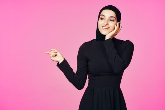 cheerful muslim woman in black hijab posing fashion pink background. High quality photo