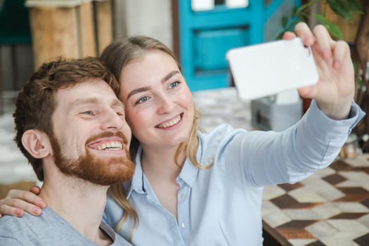 Content man and woman posing for selfie using smarpthone.