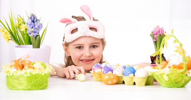 Happy smiling child peals from behind traditional and beatiful Easter decorations, isolated on white background