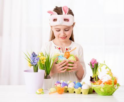 Smiling girl with vine basket of celebrative items, prepared for Easter, on white background