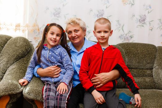 Grown up adult smiling grandchildren embraces elderly grandmother glad to see missing her, visit of loving relatives enjoy communication, cuddle as symbol of connection, love and support concept