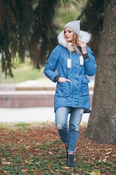 In love with nature, a girl in a jacket walks through the autumn park. warm clothes for the autumn season. woman in a hat is enjoying the fall. walks in the park.