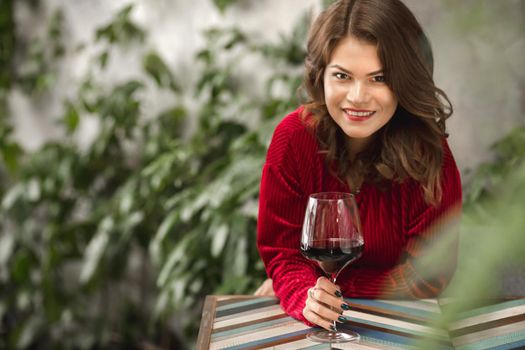 A flirtatious look of a charming girl with a glass of red wine