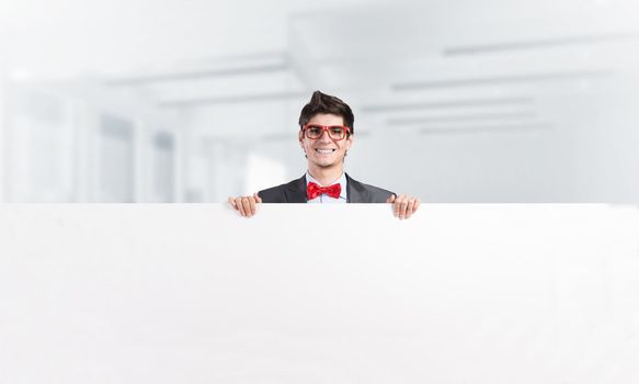 Young businessman holds a banner in front of him with two hands. Place for text