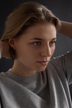 beauty portrait of caucasian woman with clean skin and short hair posing in gray t-shirt on black studio background, close up. model tests of pretty girl in basic clothes. attractive female poses