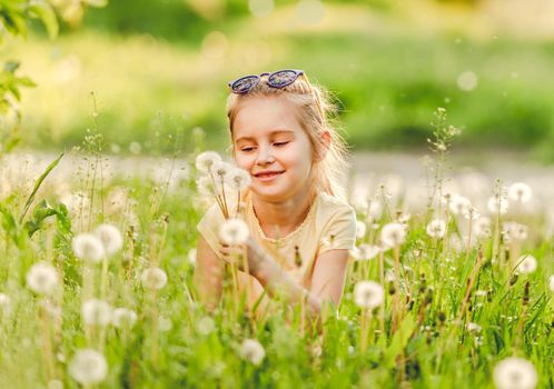 Child playing on the nature, on meadow, with flowers dandelions