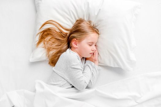 cute little girl with toy sleeping in white bed