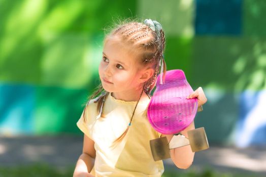cute little girl with a skateboard on her shoulder in the afternoon in the park