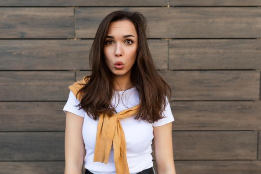 Photo of emotional positive happy joyful pretty young brunette woman in trendy outfit. Beautiful attractive female person standing outside in the street and showing sincere emotions.