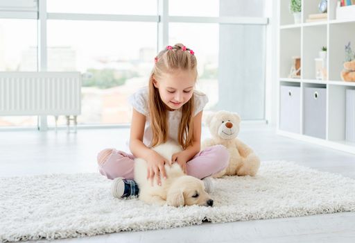 Cute girl palming retriever sitting next to teddy bear toy