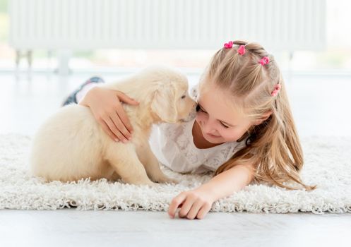 Playful puppy smells happy girl in light room