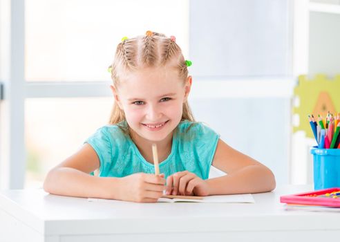 Elementary school girl doing task with pencil indoors