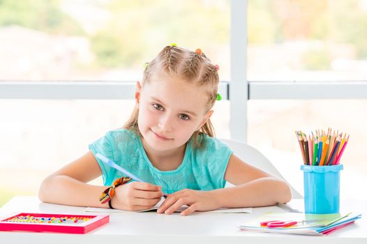 Smiling school girl sitting behind desk in class room