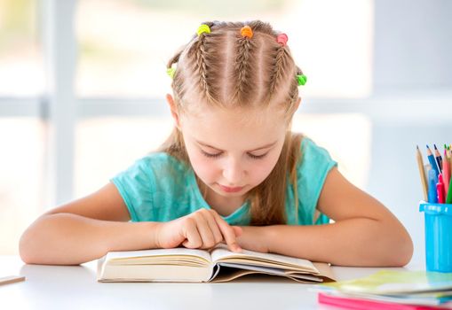 Schoolgirl reading book in light classroom