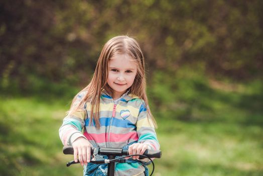 Small happy toddler girl with cool modern scooter on blurry background