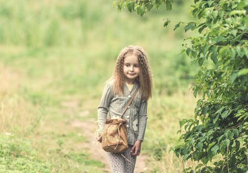 cute little girl is walking in the summer wood