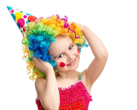 Positive little girl poses holding her head in colorful clown wig isolated on white background