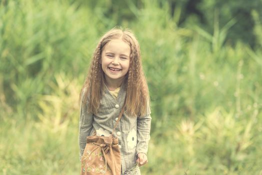 cute little girl is walking in the summer wood