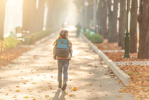 Rear view of school kid in autumn park