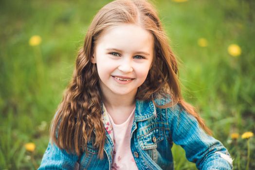 Amazingly happy girl collecting dandelions on green field