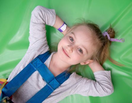 Little smiling girl laying on green soft play gym mat