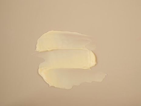 Cosmetic products creamy yellow texture stain nude beige background. The texture of natural cosmetics hair mask, cream, scrub