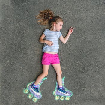 Sweet girl in roller skates painted with chalk on asphalt. top view