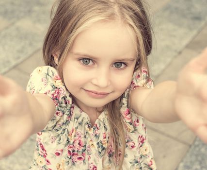 Close up self-portrait of blonde young girl with charming eyes in flower dress.