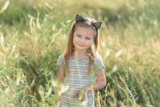 Little happy girl at sunset in the field