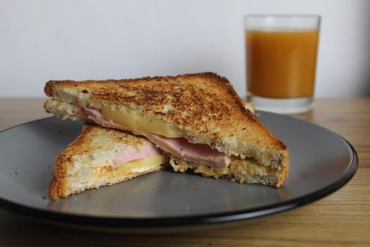 Food, avtrak. Sandwiches with ham cheese and vegetable elenium lie on a gray plate next to the juice of orange apricot on the table. Cooking breakfast.