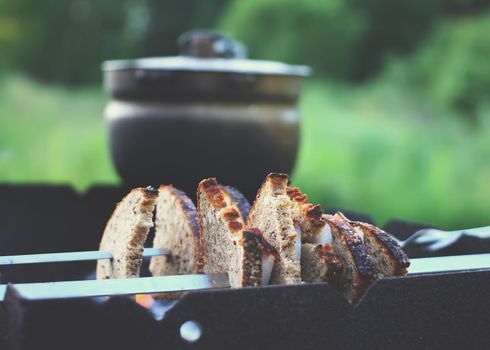 Grilling meat and bread on skewer over the brazier.