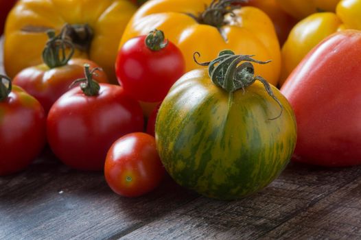 Colorful tomatoes on rustic wooden background.