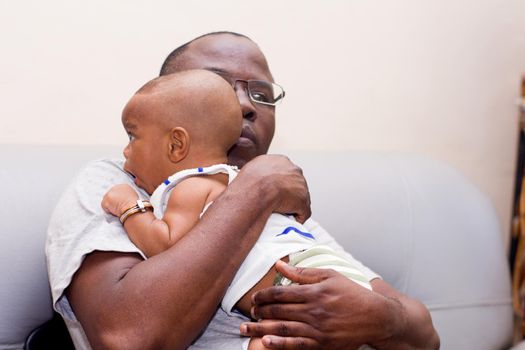 father and baby having fun at home. Proud African father holding an infant in arms while playing.