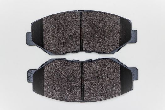 Two brake pads on a flat surface. Set of spare parts for car brake repair. Details on white background, copy space available. UHD 4K.