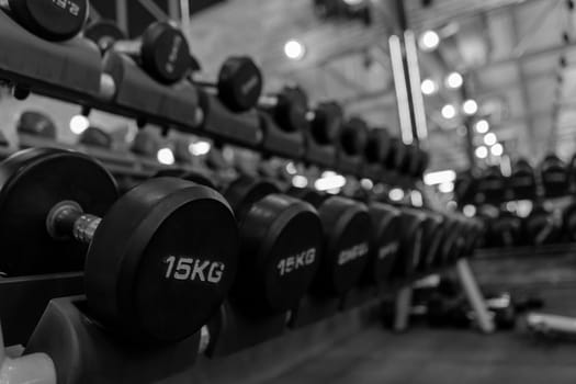 Many dumbbells on the rack in Fitness Gym. Background fitness equipment. Workout Machine concepts.