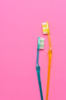 Two toothbrushes on a pink and blue background. Flay lay high angle view with copy space.