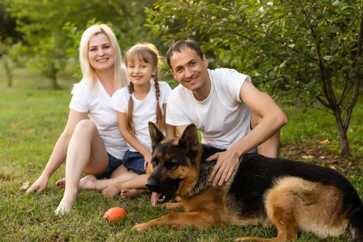 Portrait of an extended family with their pet dog sitting at the park