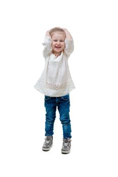 Adorable laughing kid in white sweater and blue jeans, holding her head, isolated