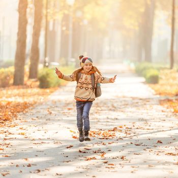 Smiling schoolchild after lessons in autumn park