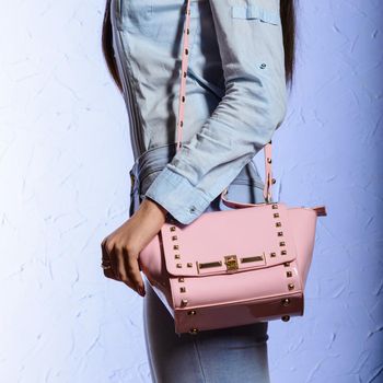 Fashion young woman in jeans with pink handbag on blue background