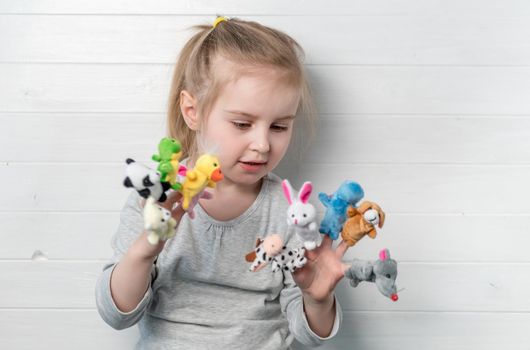 Lovely small girl with doll puppets on her hands, smiling and playing