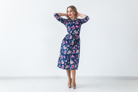 Fashionable young woman in beautiful dress posing at studio. Isolated over white.