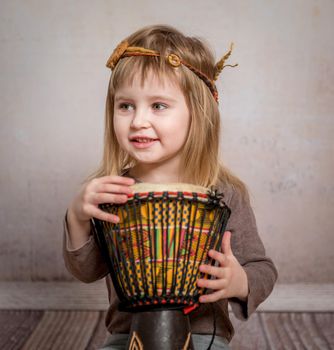 cute little girl with headband playing drum on the floor