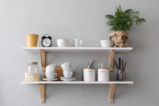 Close-up shelf with cups and different utensils.