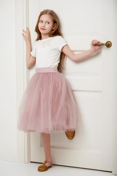 A nice little girl is standing by the door. The concept of family happiness and a home.