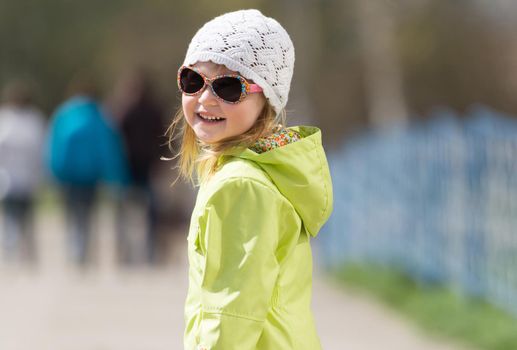 portrait of little smiling girl in sunglasses in a park in spring
