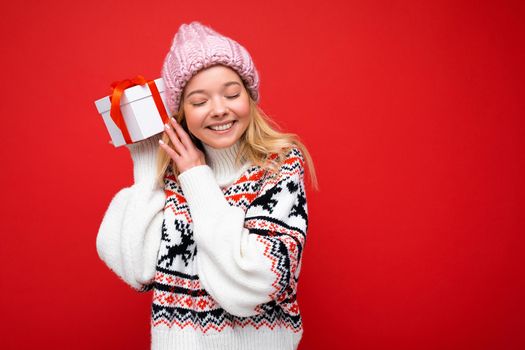 Shot of attractive positive smiling young blonde woman isolated over colourful background wall wearing everyday trendy outfit holding gift box and having fun. Copy space, mockup